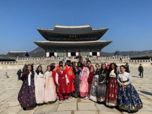 A group dressed in traditional Korean hanbok in front of a historic palace.