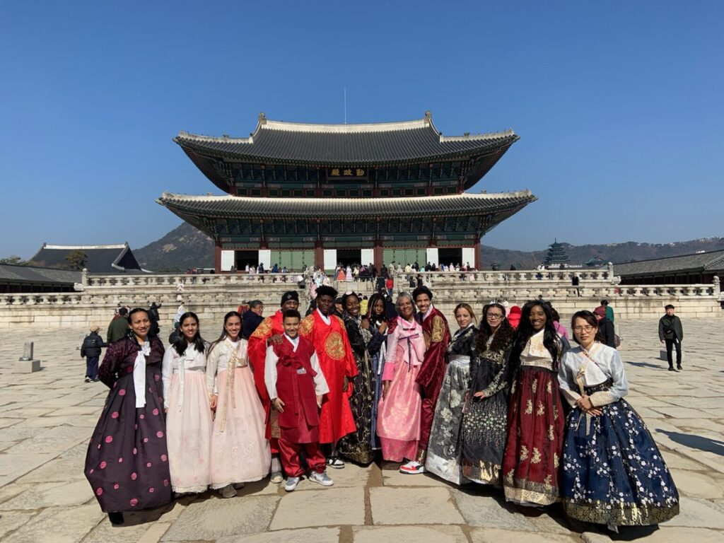 Group in traditional attire at Korean palace.